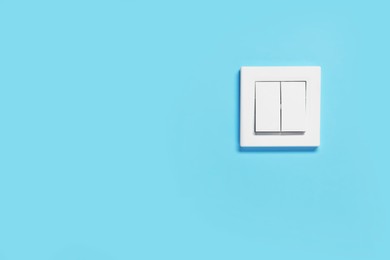 Photo of Modern plastic light switch on blue wall, space for text