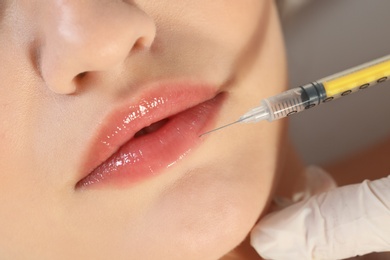 Photo of Young woman getting lips injection, closeup. Cosmetic surgery