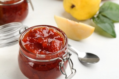 Photo of Delicious quince jam on white table, closeup