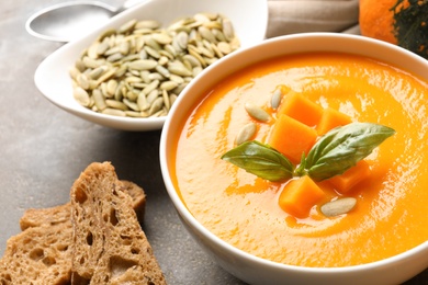 Bowl with tasty pumpkin soup served on gray table