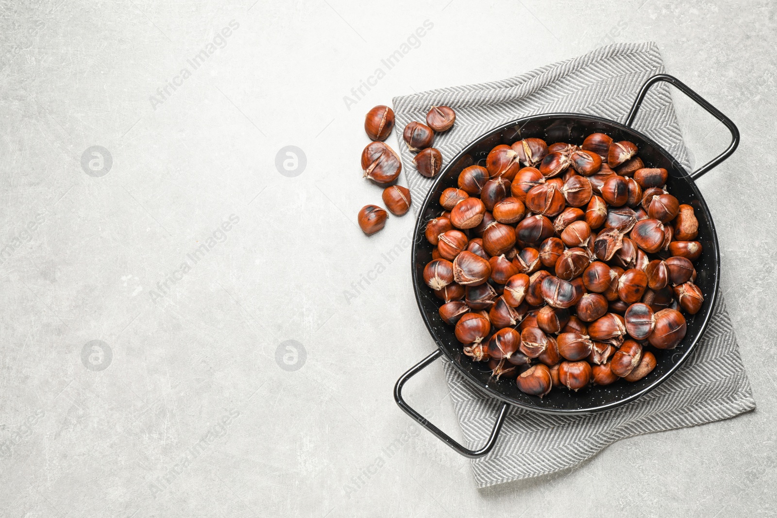 Photo of Delicious roasted edible chestnuts on light grey table, flat lay. Space for text