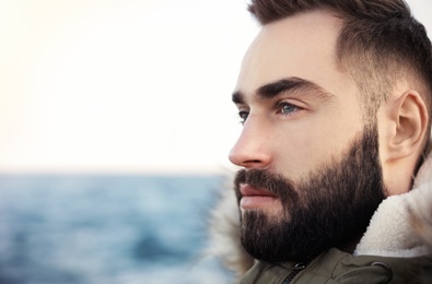 Photo of Portrait od bearded handsome man near sea, closeup view. Space for text
