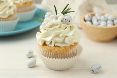 Photo of Tasty Easter cupcakes with vanilla cream on light wooden table