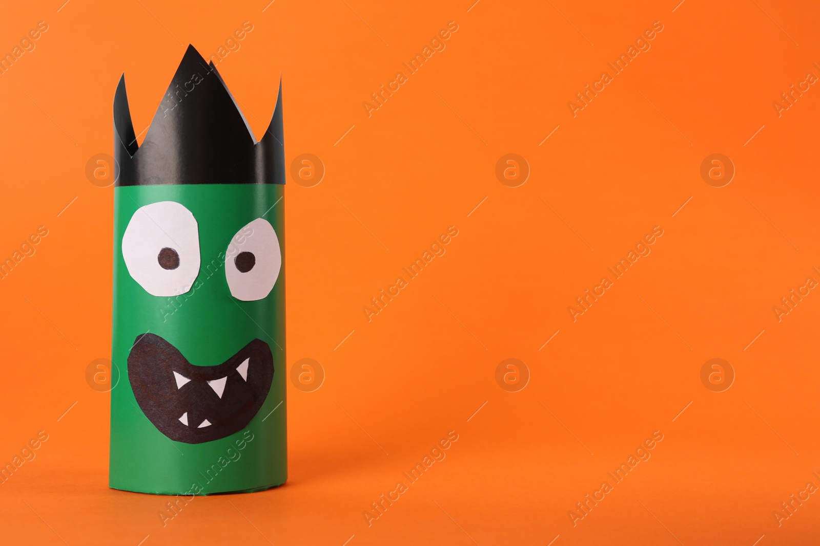 Photo of Funny green monster on orange background, space for text. Halloween decoration