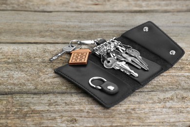 Photo of Open leather holder with keys on old wooden table. Space for text