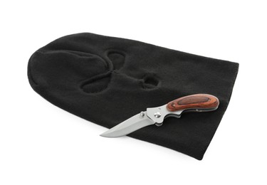 Black knitted balaclava and knife on white background