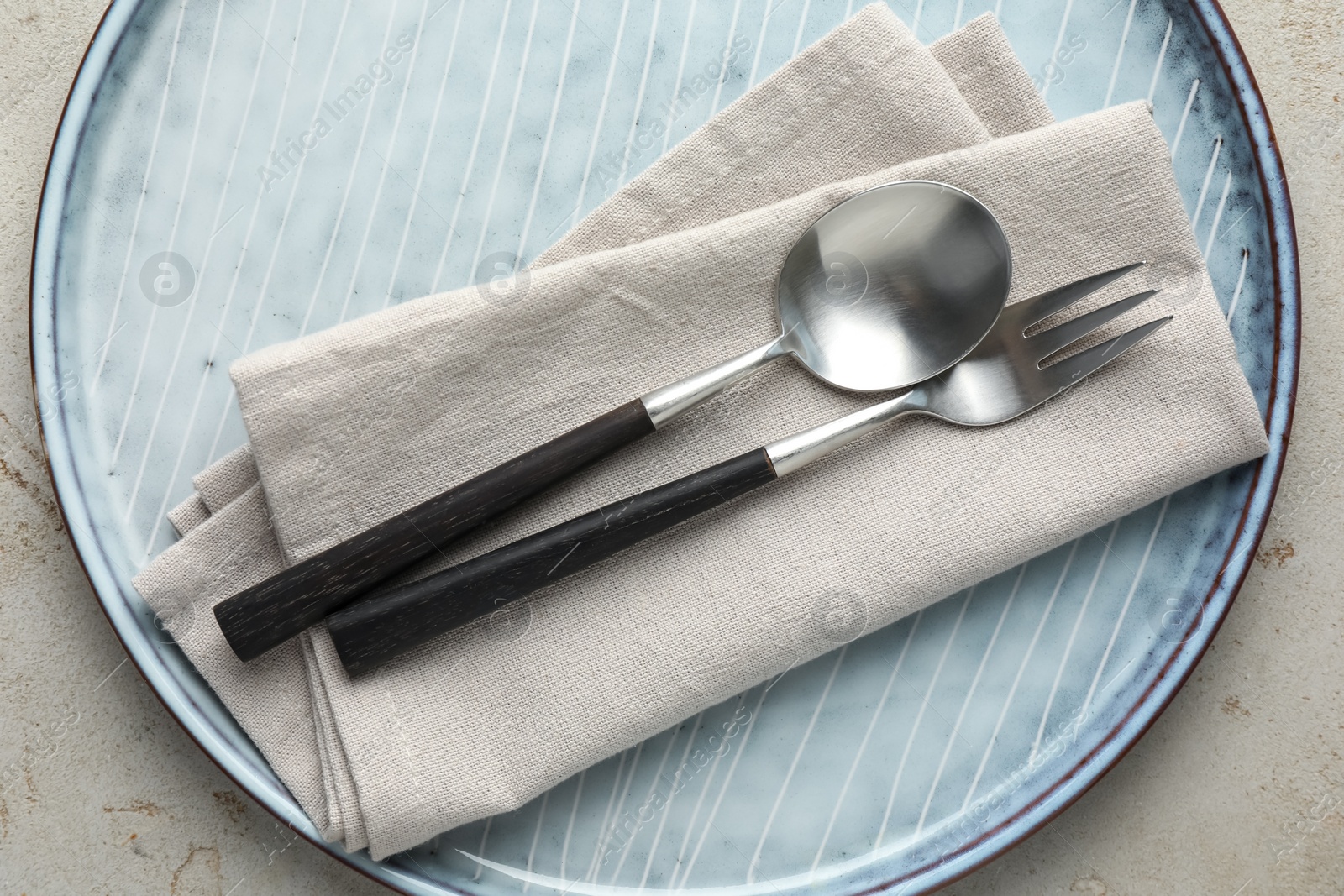 Photo of Stylish setting with cutlery, napkin and plate on light grey table, top view