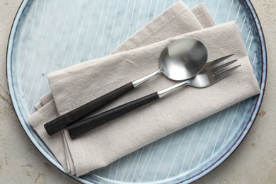 Stylish setting with cutlery, napkin and plate on light grey table, top view