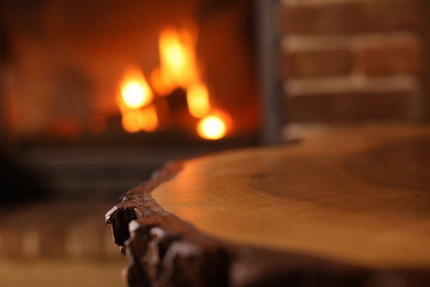 Photo of Stylish wooden table and blurred fireplace on background, closeup. Winter vacation