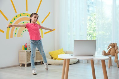 Photo of Cute little girl taking online dance class at home