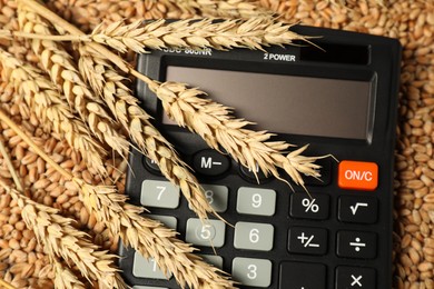 Calculator and wheat ears on grains, closeup. Agricultural business