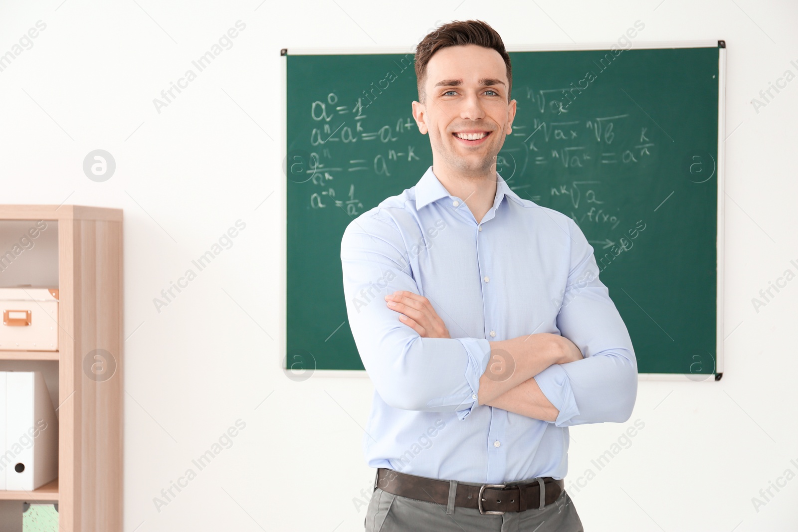 Photo of Young male teacher standing in classroom