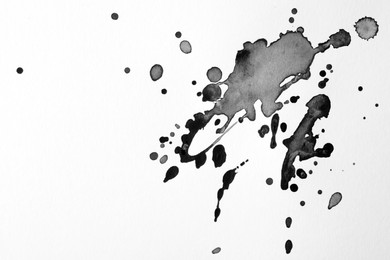 Photo of Blots of black ink on white background, flat lay. Space for text