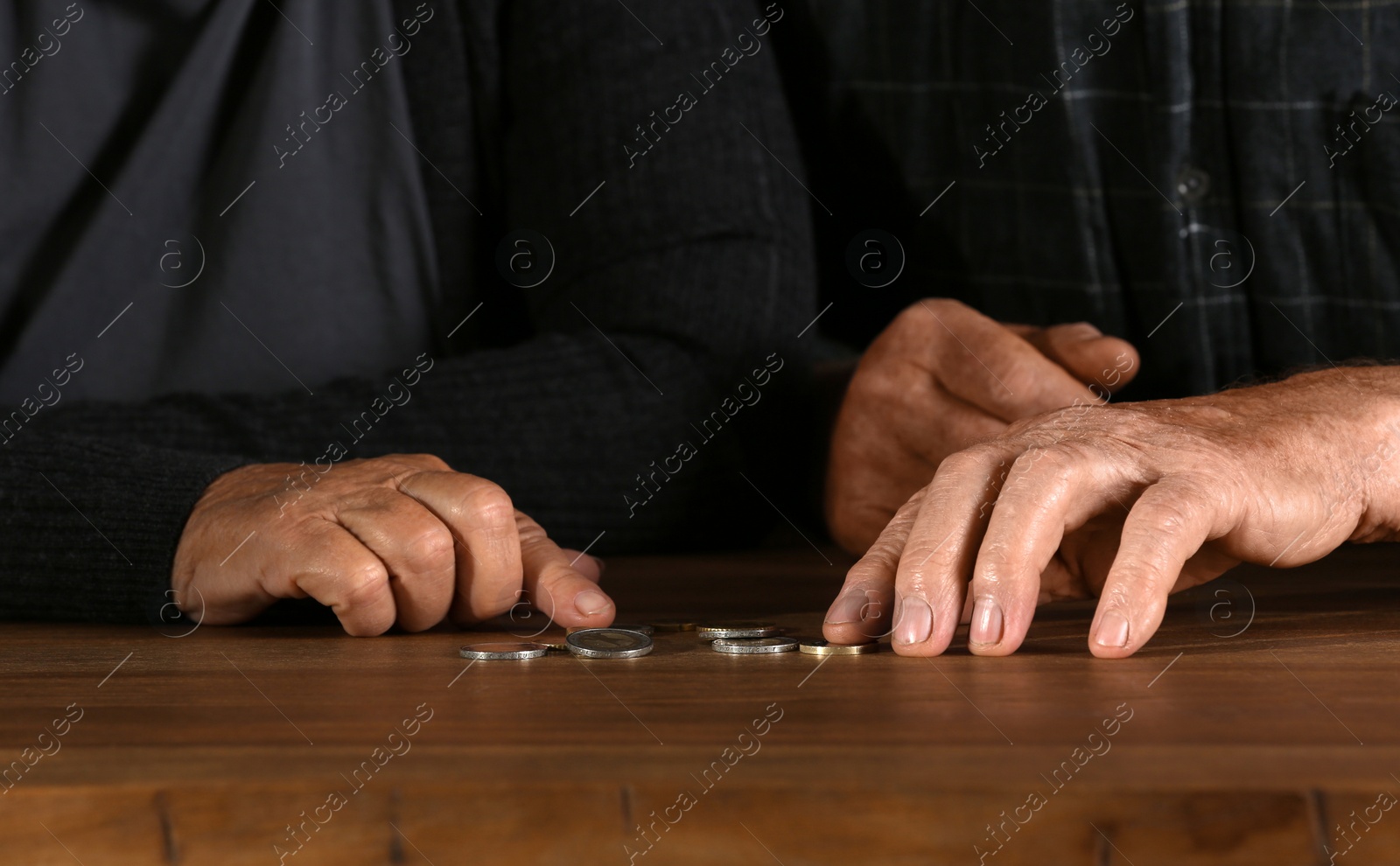 Photo of Poor elderly couple counting coins at table, focus on hands