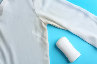 Clothes with stain and deodorant on light blue background, top view