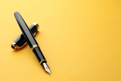 Photo of Stylish fountain pen with cap on yellow background. Space for text