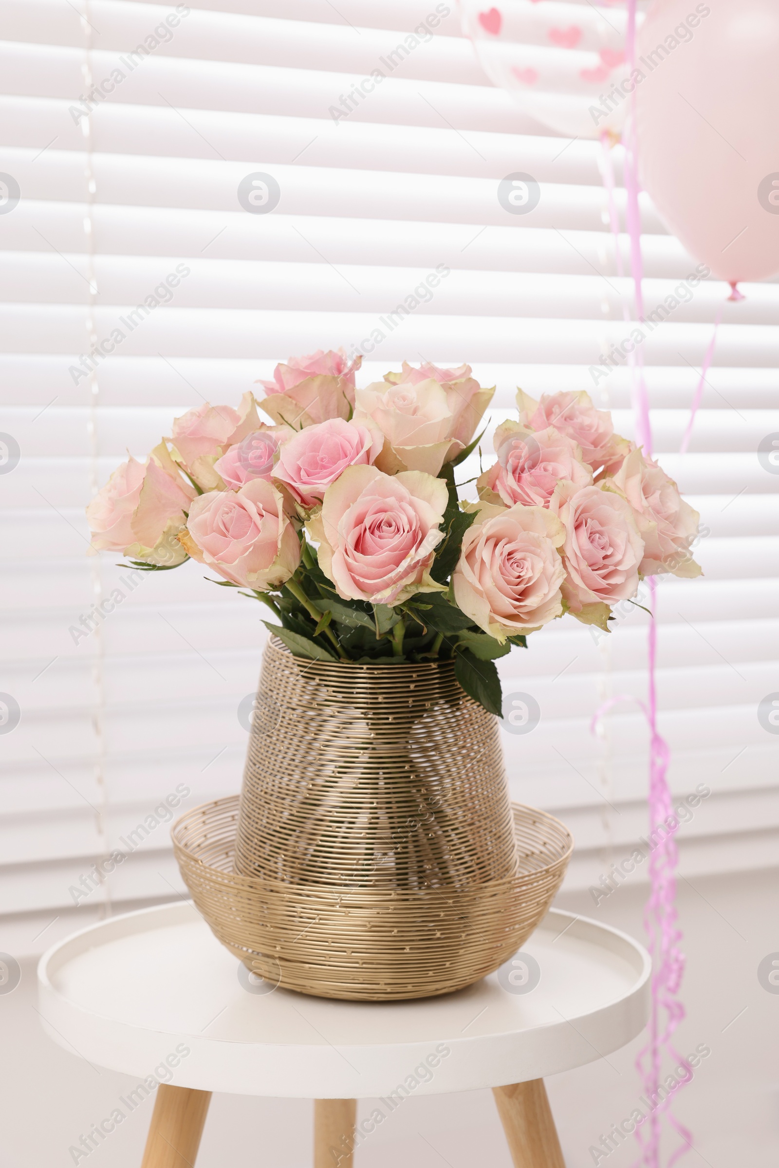 Photo of Beautiful roses on coffee table and air balloons in room. Happy birthday