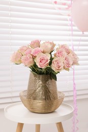 Photo of Beautiful roses on coffee table and air balloons in room. Happy birthday