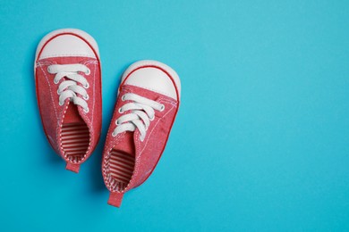 Cute baby shoes on light blue background, flat lay. Space for text