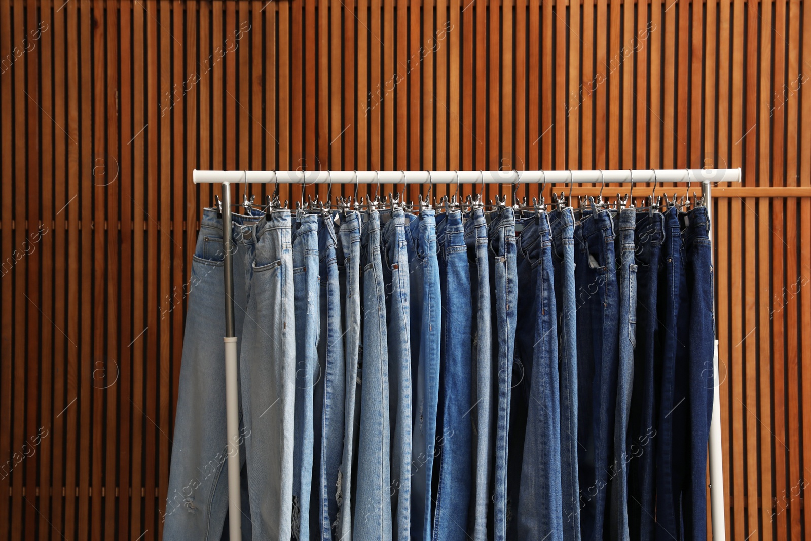 Photo of Rack with different jeans on wooden background