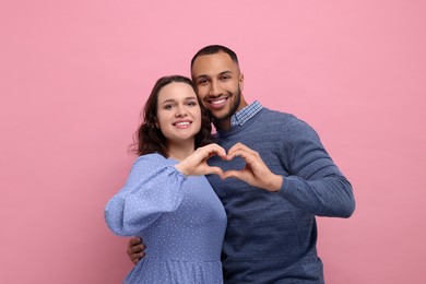 Photo of Lovely couple making heart with hands on pink background. Valentine's day celebration