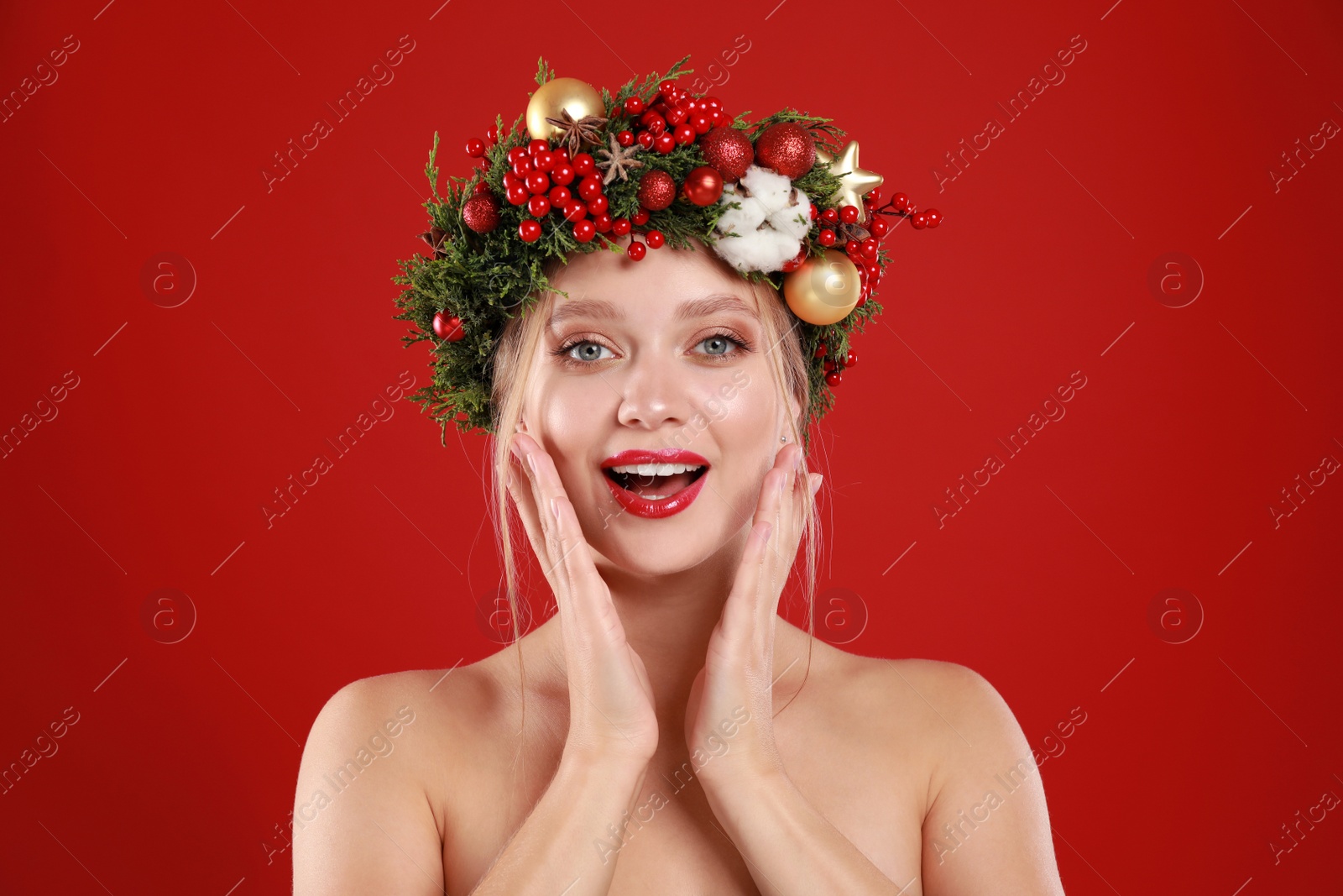 Photo of Beautiful young woman wearing Christmas wreath on red background