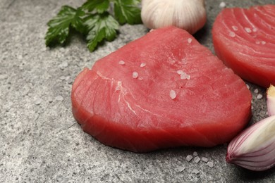 Photo of Raw tuna fillets with spices and shallot on gray table, closeup