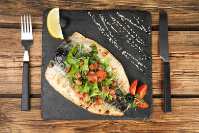 Photo of Delicious grilled fish served on wooden table, flat lay