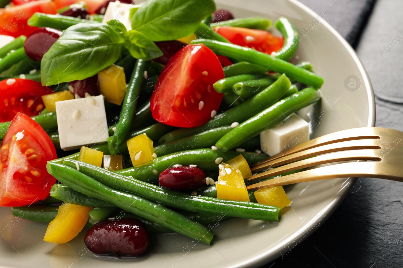 Photo of Tasty salad with green beans served on black table, closeup