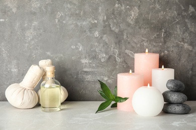 Spa composition with burning candles and essential oil on table, space for text