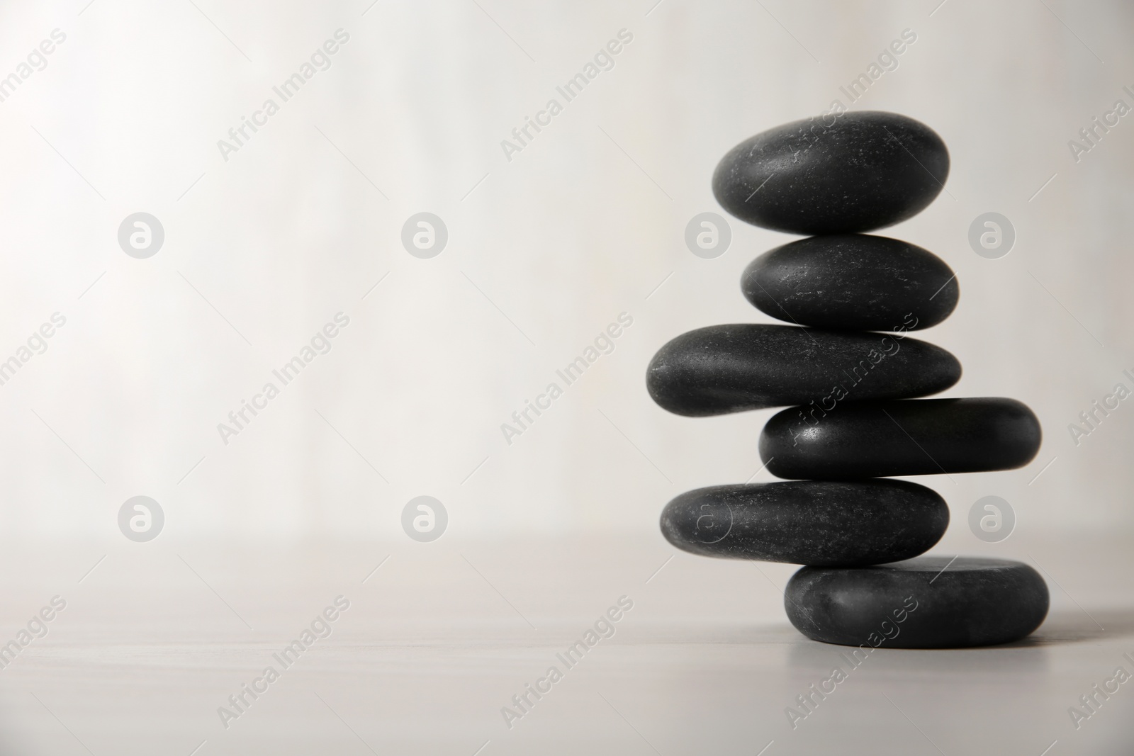 Photo of Stack of black spa stones on light background. Space for text