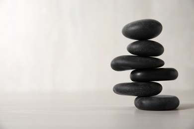 Stack of black spa stones on light background. Space for text