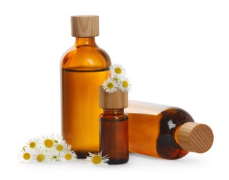 Photo of Bottles of chamomile essential oil and flowers on white background