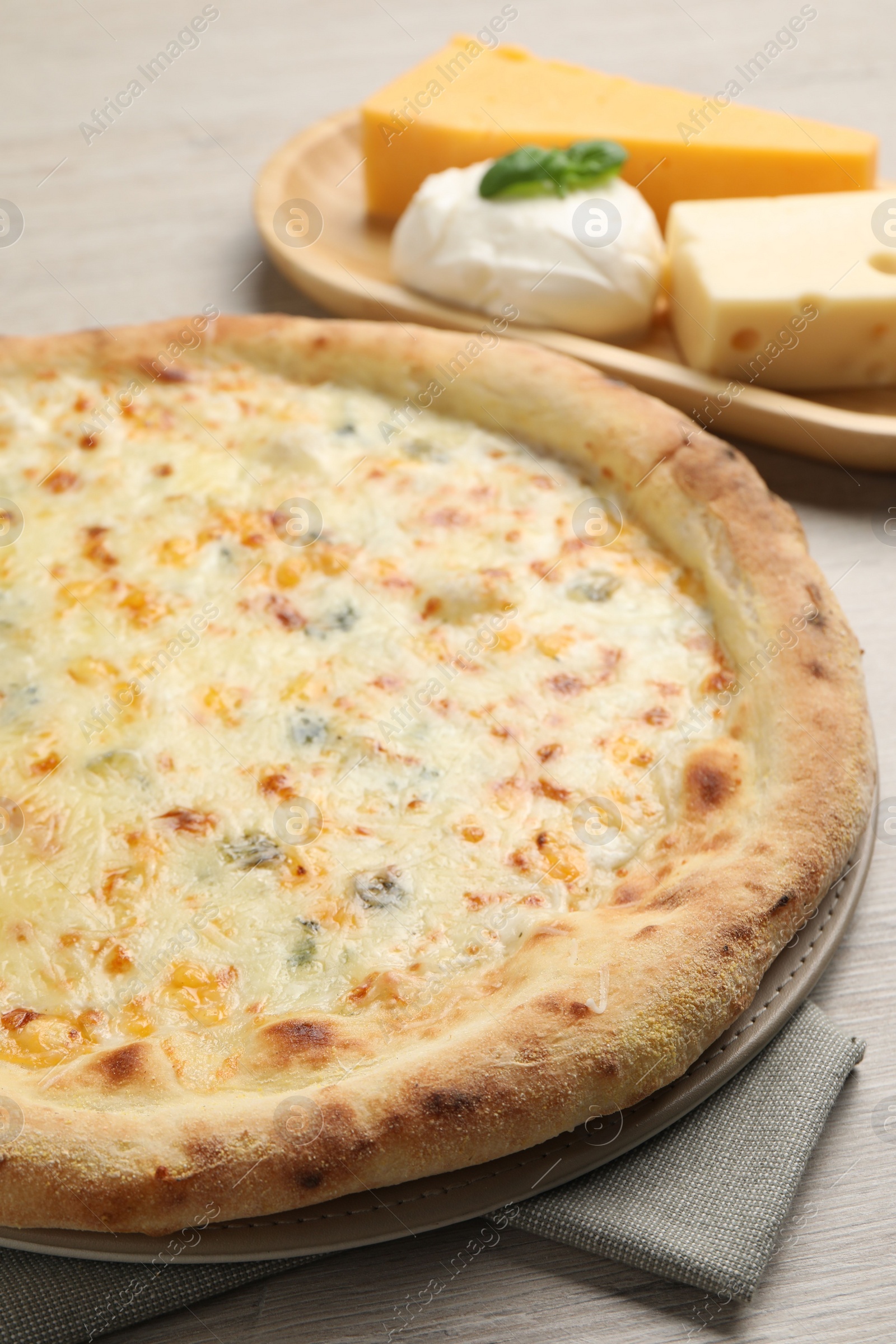 Photo of Delicious cheese pizza and different kinds of cheese on wooden table, closeup