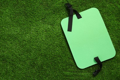 Photo of Bright foam tourist seat mat on green grass, top view. Space for text