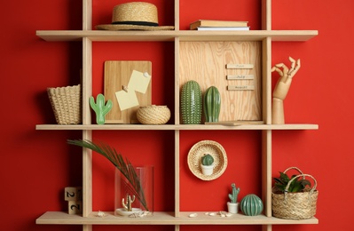 Stylish wooden shelves with decorative elements on red wall