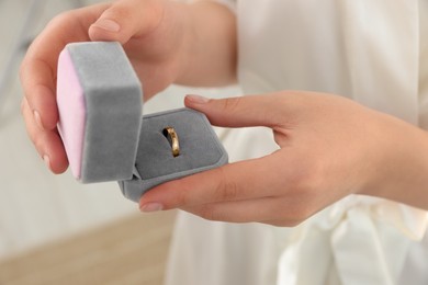 Bride holding box with engagement ring indoors, closeup. Wedding day