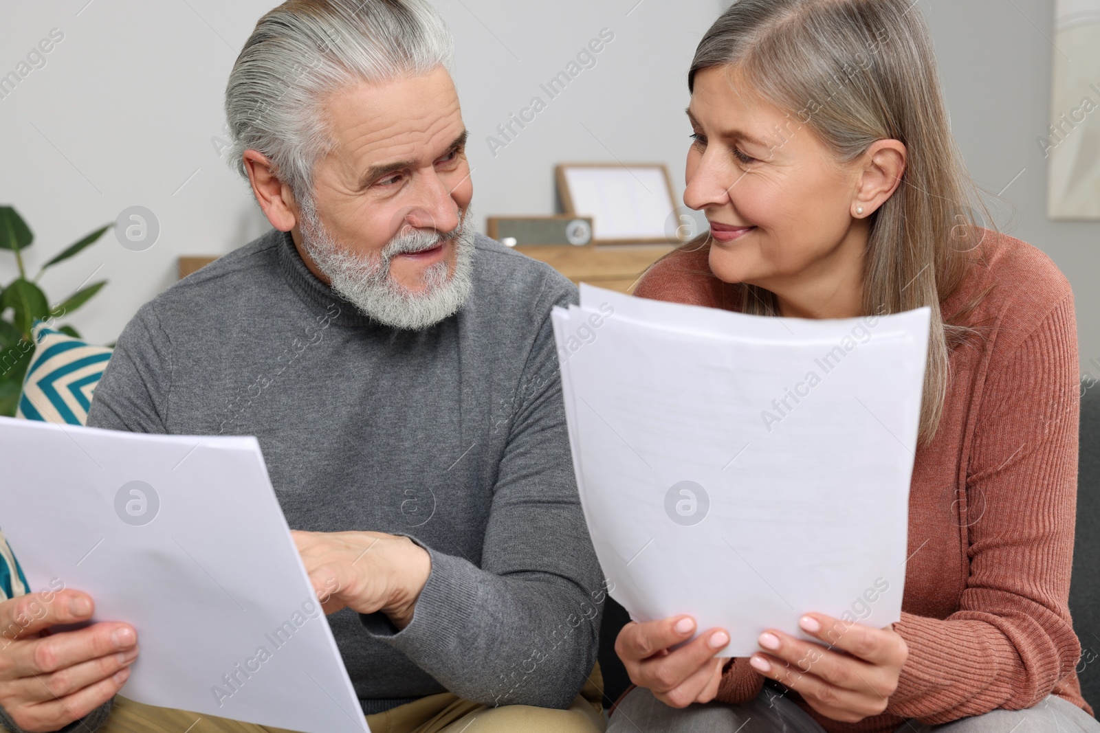 Photo of Elderly couple with papers discussing pension plan in room