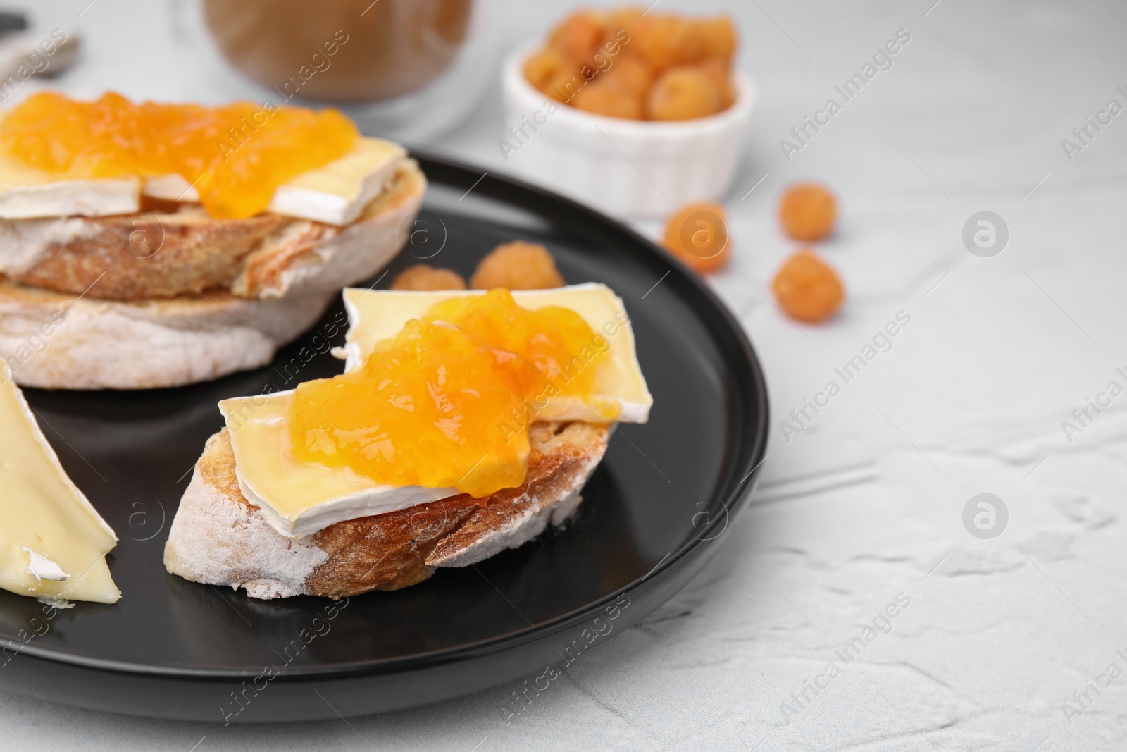 Photo of Tasty sandwiches with brie cheese, fresh raspberry and apricot jam on white textured table, closeup. Space for text