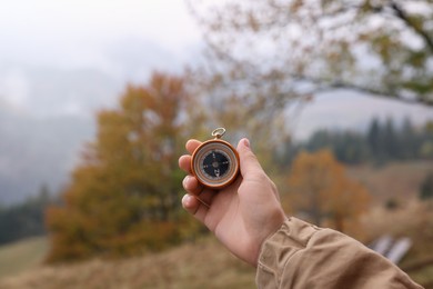 Photo of Woman using compass for navigation during journey in mountains, closeup