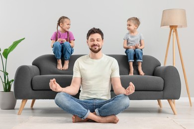 Photo of Father meditating while his children sitting on sofa at home