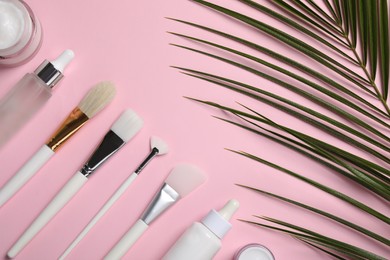 Photo of Different skin care products and brushes on pink background, flat lay