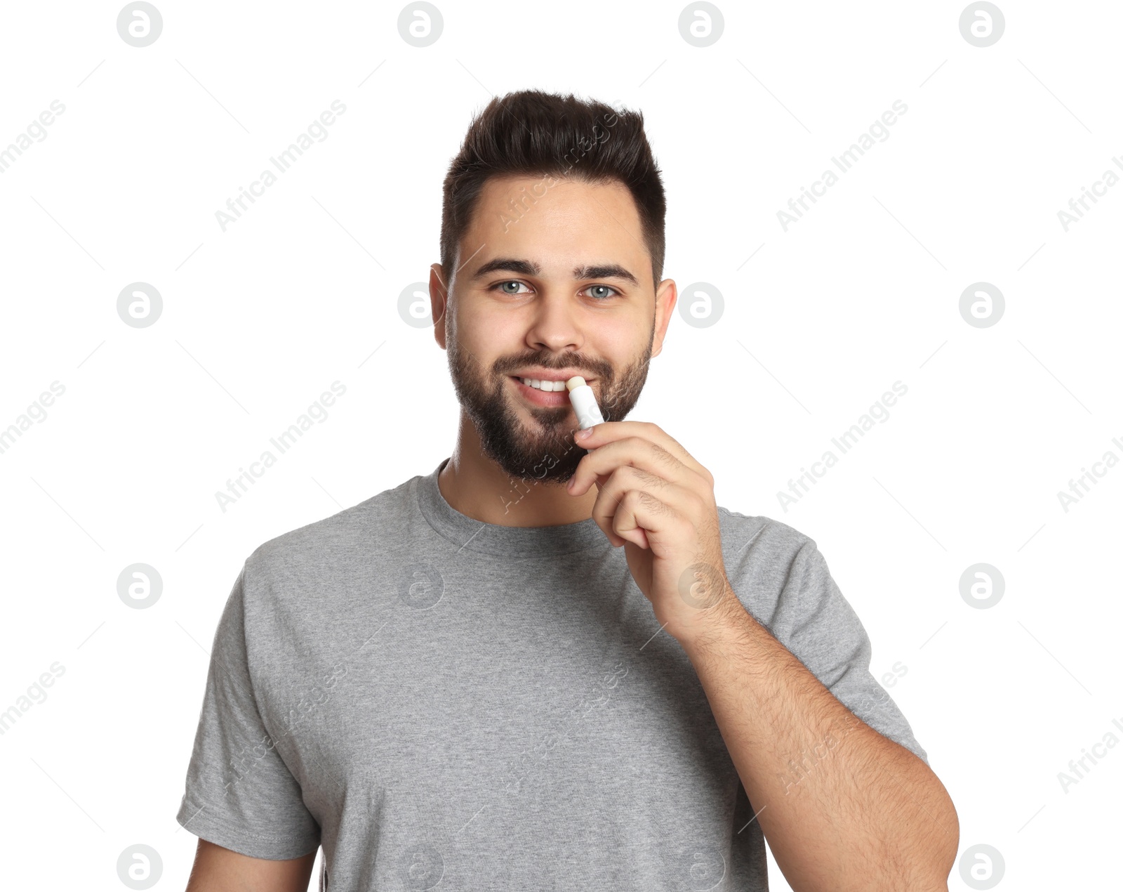 Photo of Young man applying lip balm on white background