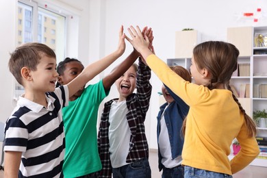 Happy children giving high five at school