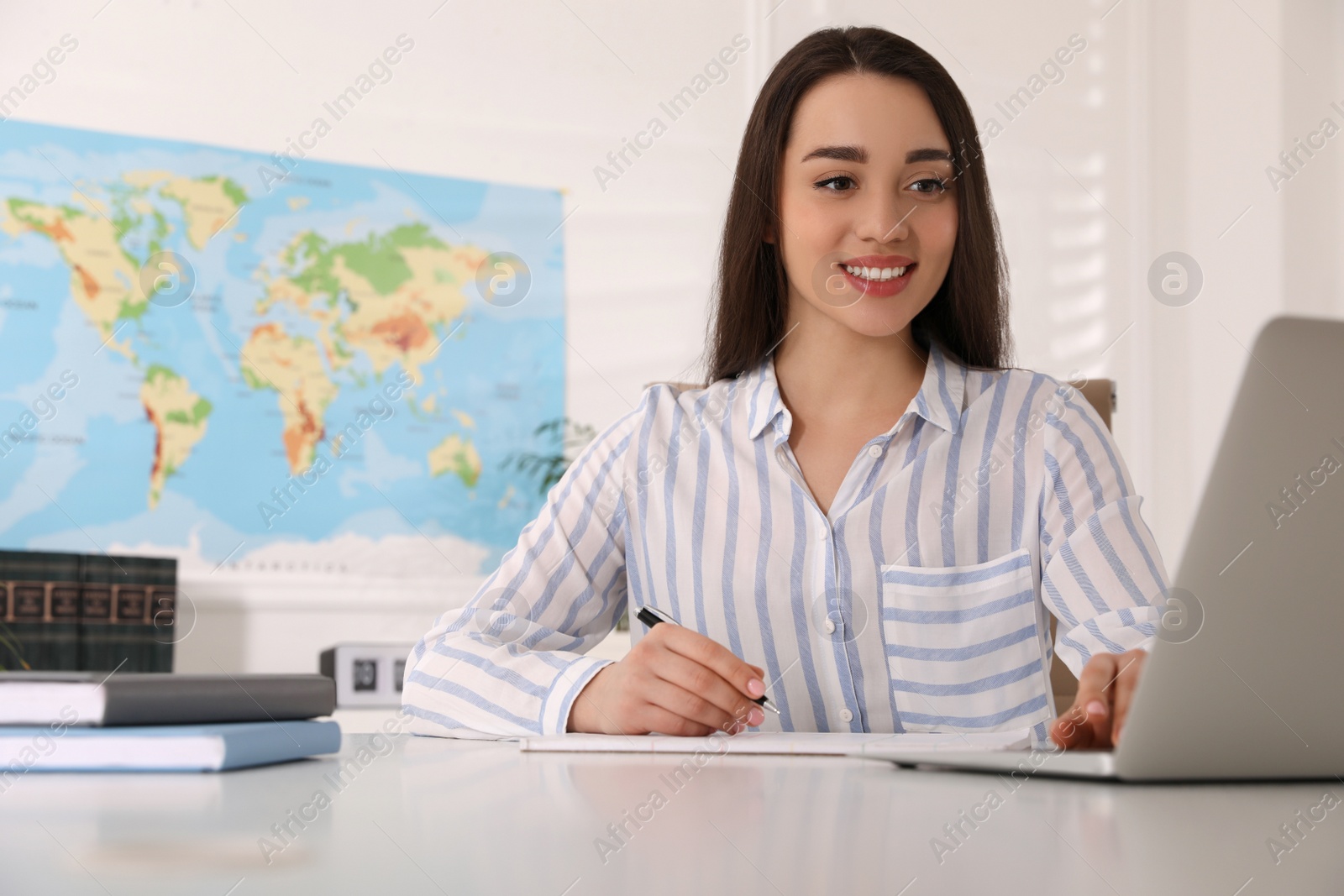 Photo of Happy manager working with laptop at desk in travel agency