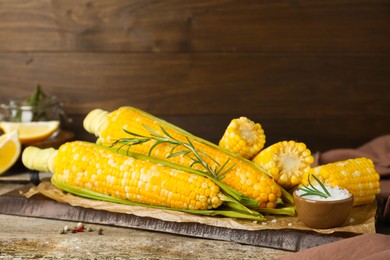 Tasty cooked corn cobs on wooden table