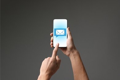 Image of Man checking new message on mobile phone against dark grey background, closeup