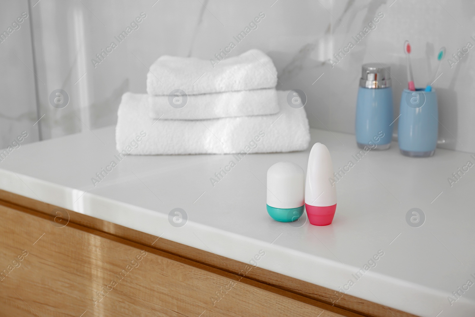 Photo of Different deodorants on light countertop in bathroom