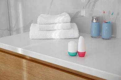 Photo of Different deodorants on light countertop in bathroom