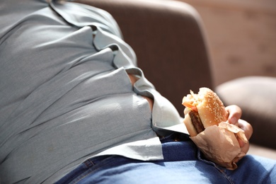 Photo of Overweight boy with burger sleeping on sofa at home, closeup view
